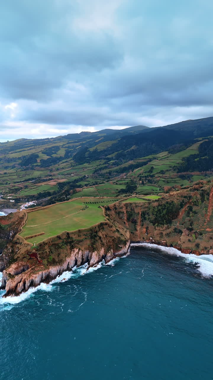 Amazing picturesque rocks with greenery on the shore of the North Atlantic Ocean. Aerial perspective on the stunning Azorean Islands. Vertical video.