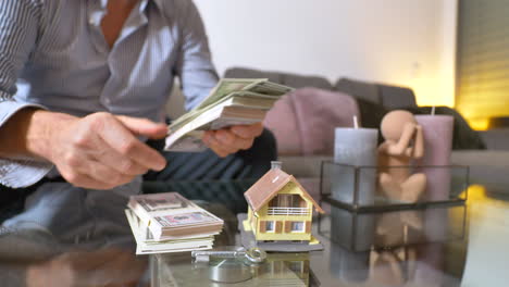 close up shot of man counting cash money on table at home for buying own real estate with villa