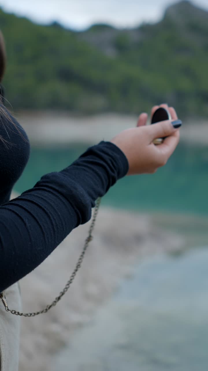 Person holding a vintage pocket watch in a scenic outdoor setting