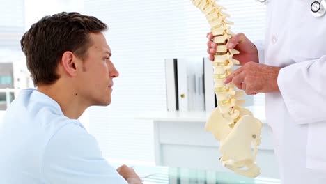 patient listening to his doctor explain spine model