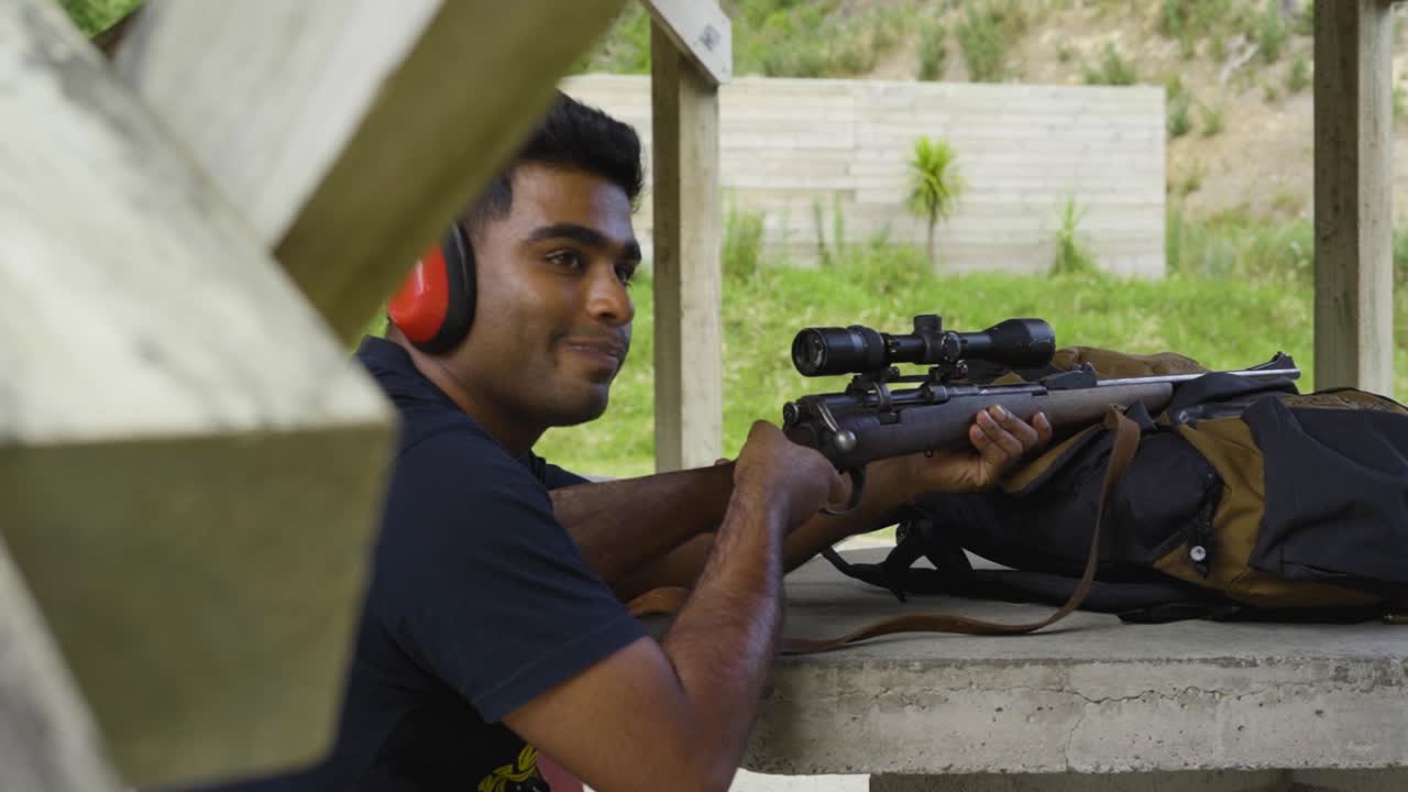 retrato de un tirador masculino sonríe a la cámara mientras apunta con una escopeta al campo de tiro