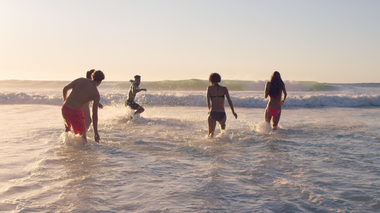 해가 지면 바다 에서 수영 하는 다양한 친구 들 의 그룹