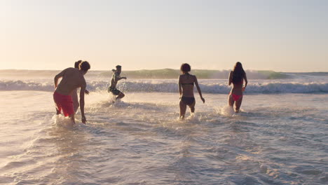 Diverse-Group-of-friends-swimming-in-the-sea-at-sunset