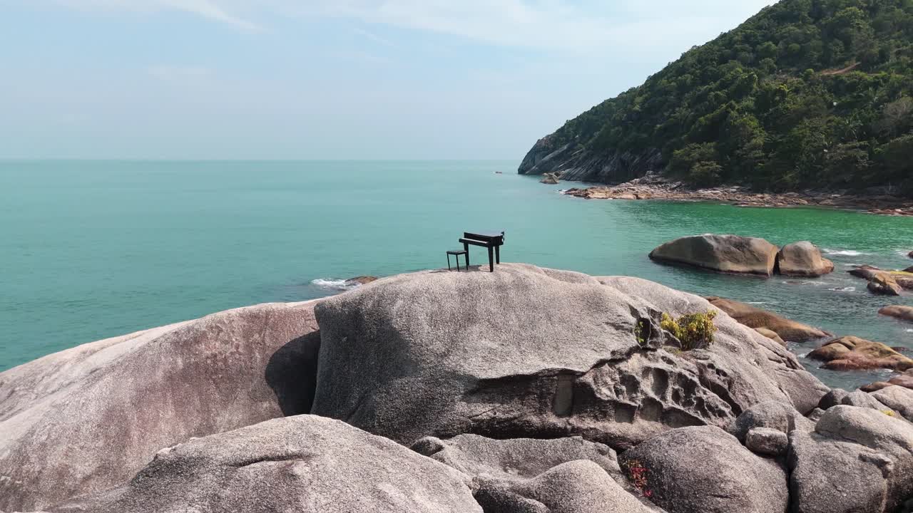Piano standing alone on rocky beach of Koh Phangan, captured by drone