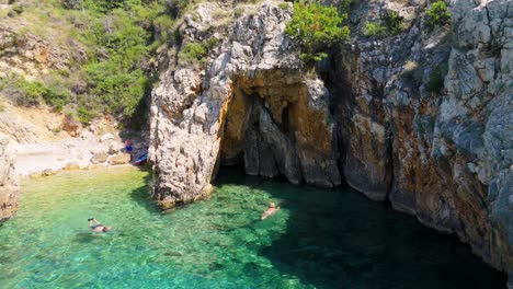 beautiful young woman in bikini swims in stara baska beach krk island, croatia. mediterranean summer. aerial shot from above. blue sea the rocks mountains and coastline calm sea with clear blue water