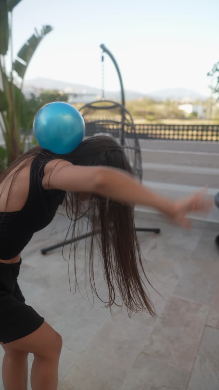 una adolescente jugando con un globo en un balcón