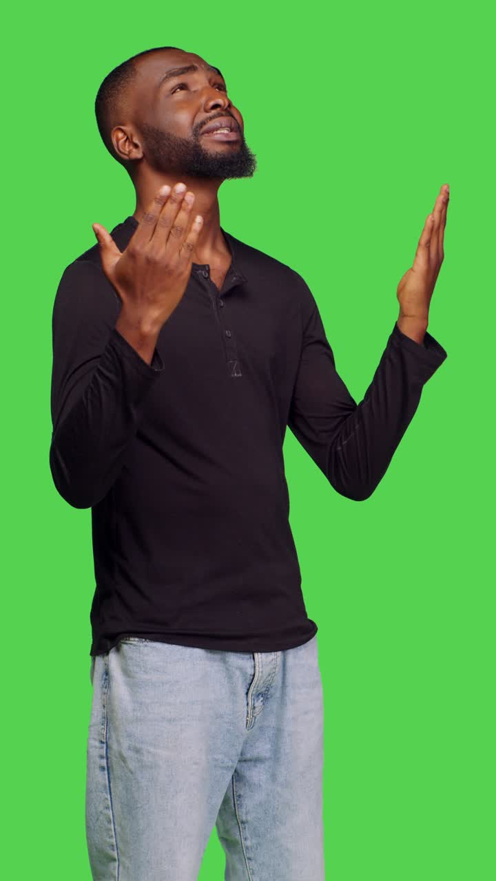 Vertical video: Side view of african american guy praying to god on camera