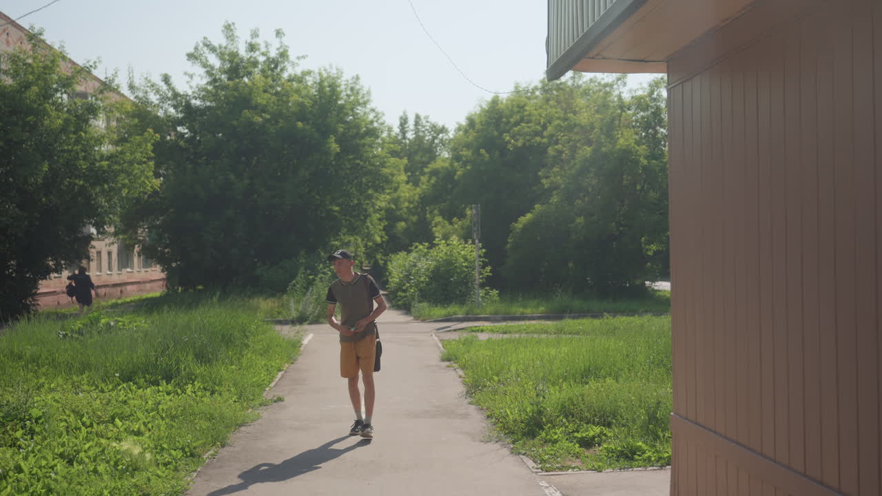 Young Male Enjoying Sunny Nature Walk, Casual Young Man Exploring Luminous Outdoor Trail, An Energetic Young Man In Relaxed Attire Saunters Along Sunny Forest Trail Holding His Cellphone