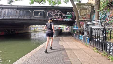 person running under graffiti-covered bridge