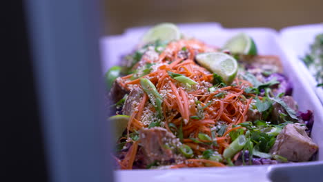primer plano de una mujer agregando limón a un plato lleno de ensalada de pollo