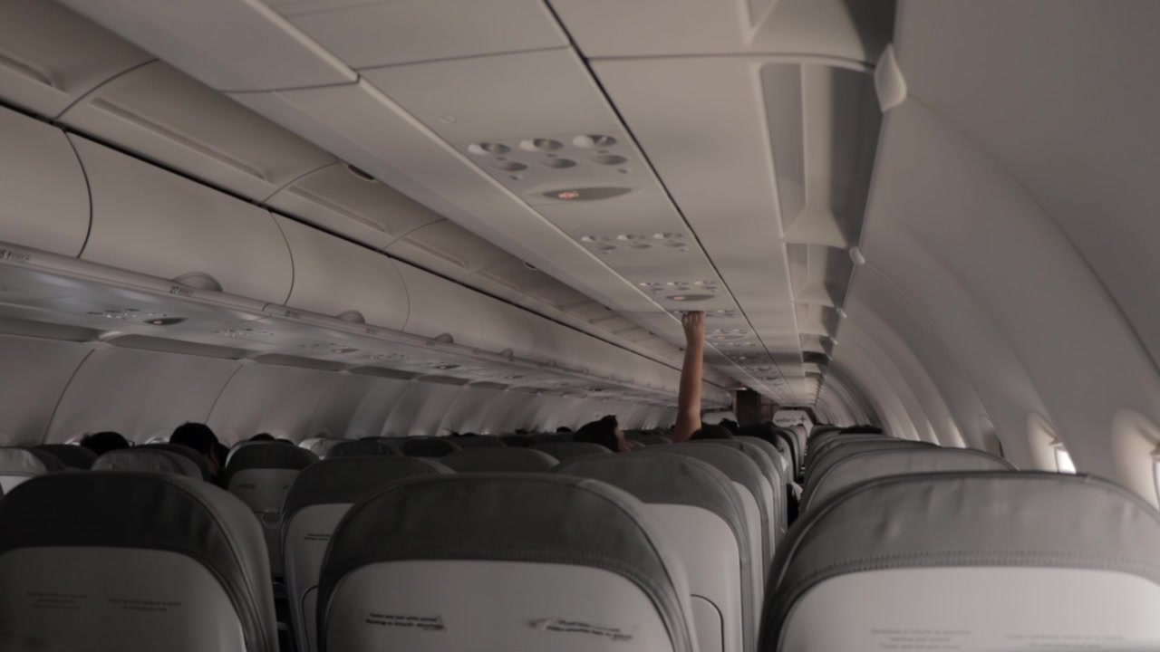 Pessoa ajustando o ar condicionado em um avião.