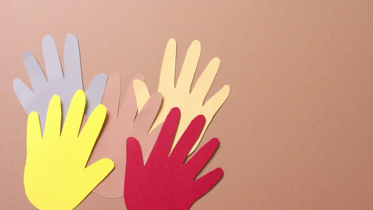 Close up of hands together made of colourful paper on brown background with copy space