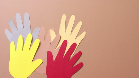 cerca de las manos juntas hechas de papel de colores sobre fondo marrón con espacio para copiar