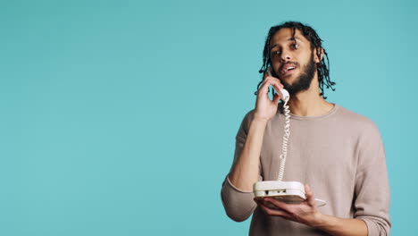 Upbeat-person-talking-with-mate-using-landline-phone,-studio-background