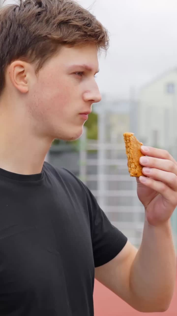 An athlete takes a break to eat a dietary snack; vertical footage