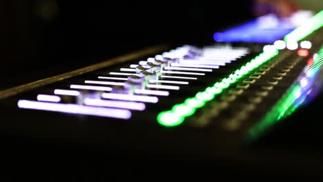 botones coloridos del mezclador moviéndose lentamente en el fondo oscuro del estudio de televisión