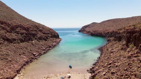 deserted coastal bay, boat and people moored on empty beach, aerial reveal