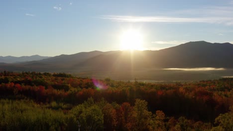 drone dolley shot over vibrant fall leaf colors during a bright sunrise over the white mountains