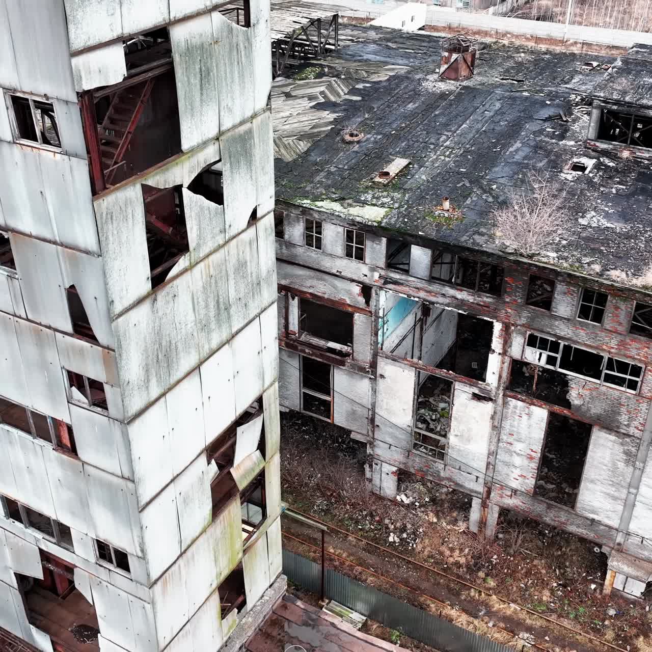 Old plant territory abandoned long ago. Grey wrecked skeletons of the industrial premises. View from above