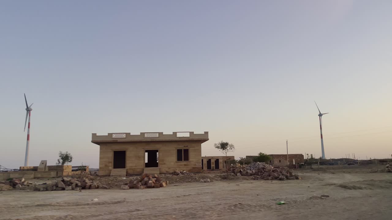Driving along Jaisalmer road, Rajasthan India windmills turn gently in the breeze. Open land stretches wide, dotted with scattered trees under a clear, endless sky a serene desert journey unfolds