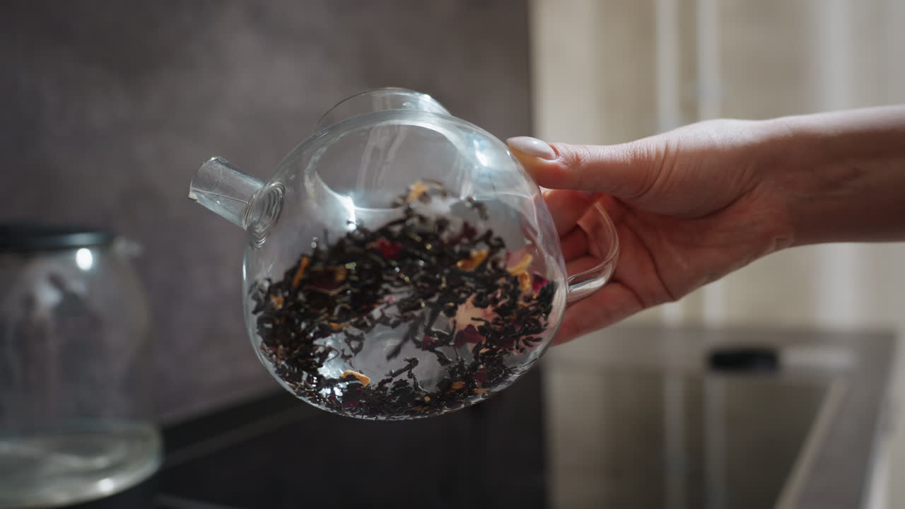 Hands Gently Pour Herbal Tea, Closeup Of Glass Teapot With Leaves, Morning Scene Of Herbal Tea Ritual In Sunlit Kitchen, Vivid Image Of Peaceful Herbal Tea Preparation In Bright Kitchen Setting