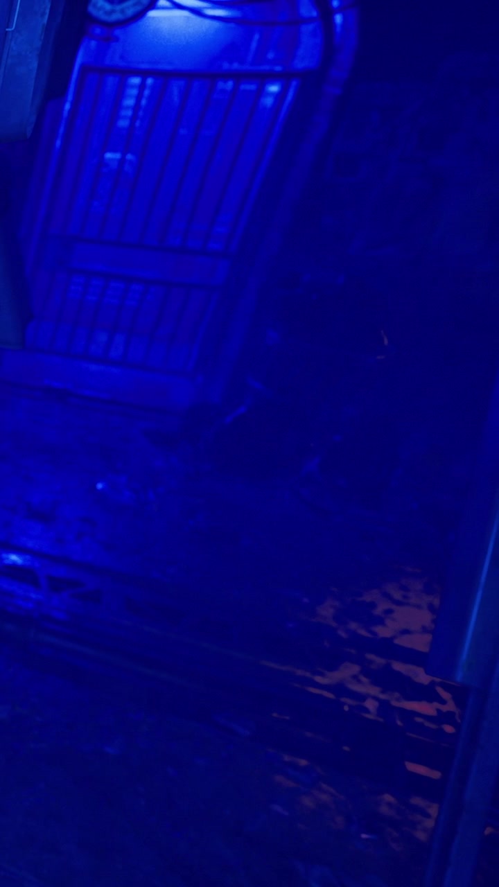 Vista di un corridoio buio con illuminazione blu in un edificio urbano di notte.