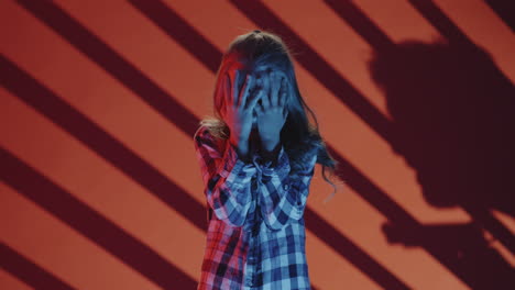 scared girl in red and blue light with shadow