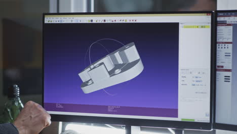 person's hand pointing at a 3d cad model on a computer screen