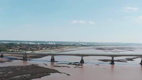 Slider-Drohnenaufnahme-Einer-Straßenseebrücke-Mit-Kraftwerk-Im-Hintergrund