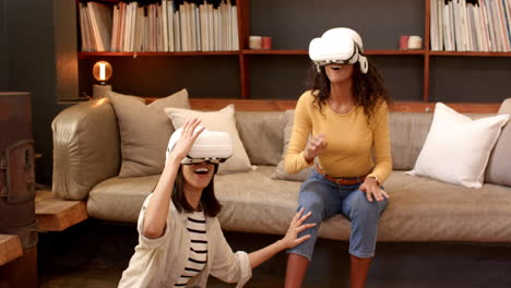 multiracial female friends enjoying virtual reality experience at home, laughing and interacting