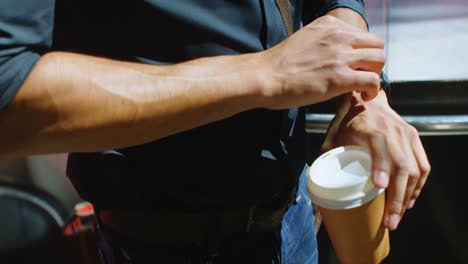 Hombre-Con-Taza-De-Café-Revisando-Reloj-Inteligente-En-La-Calle-4k