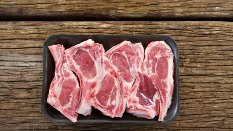 Sirloin-steak-in-black-container-on-wooden-background