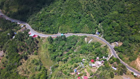 winding road through lush green mountainside with houses in bocas del toro, panama. aerial shot