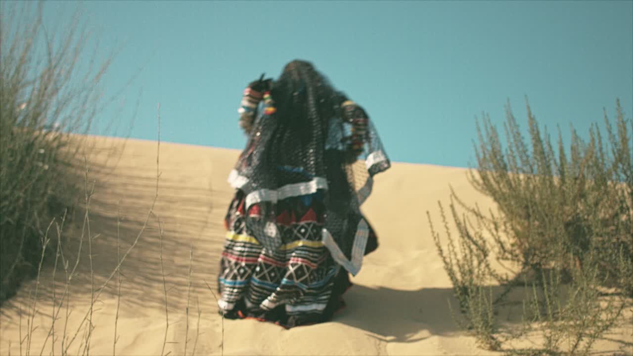 mujer gitana escalando en una duna de arena del desierto
