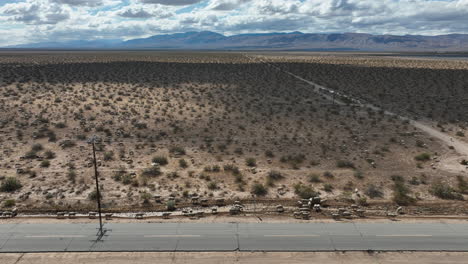 flock of sheep along a rural road in the mojave desert - aerial