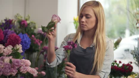 young female florist business owner working and preparing flower arrangements in her shot, with fresh flowers. she is