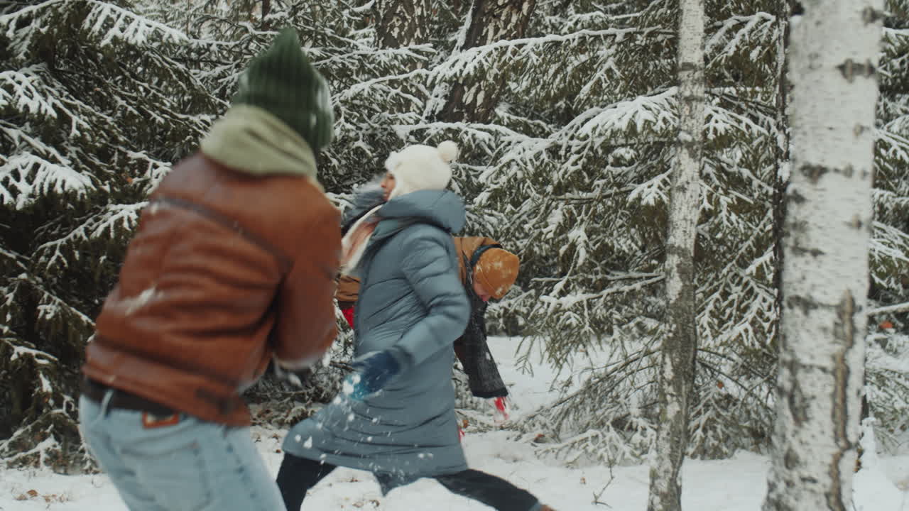 amigos teniendo una pelea de bolas de nieve en el bosque de invierno