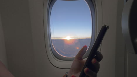 using mobile in the plane aircraft window with sunrise in background