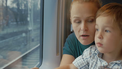 Mother-and-son-looking-out-train-window