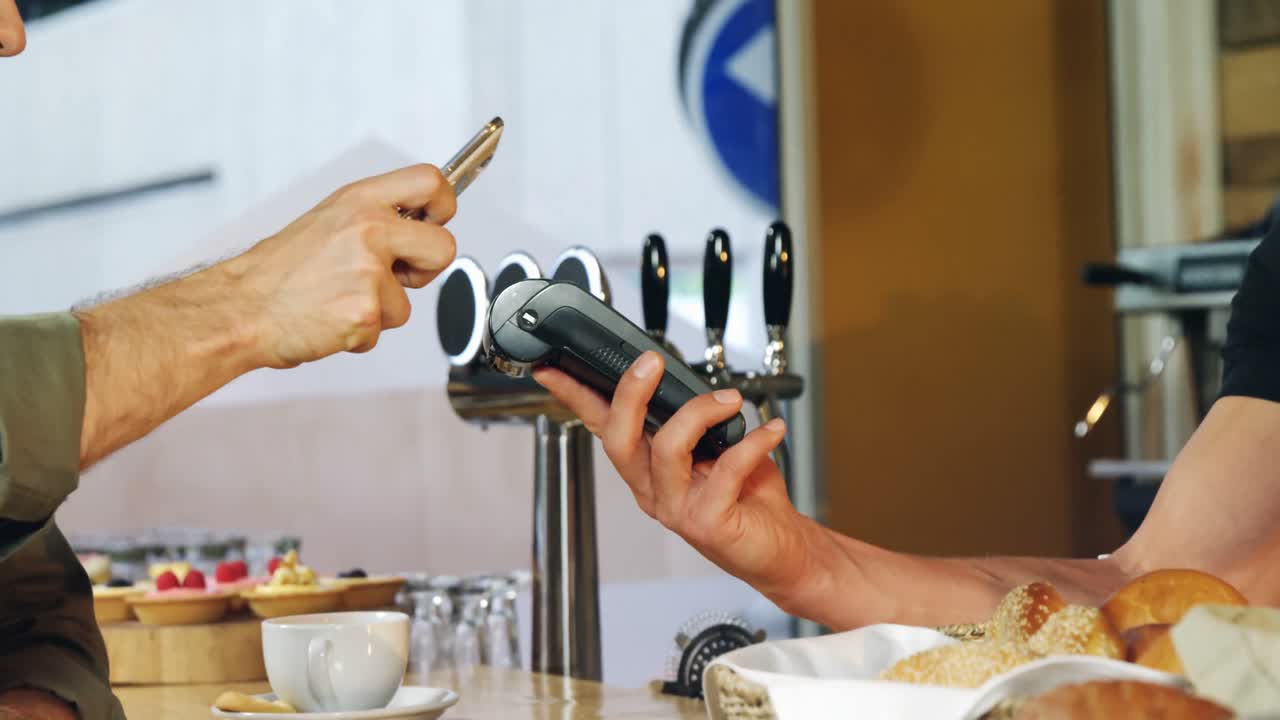 cliente haciendo pago a través de teléfono móvil en el mostrador 4k