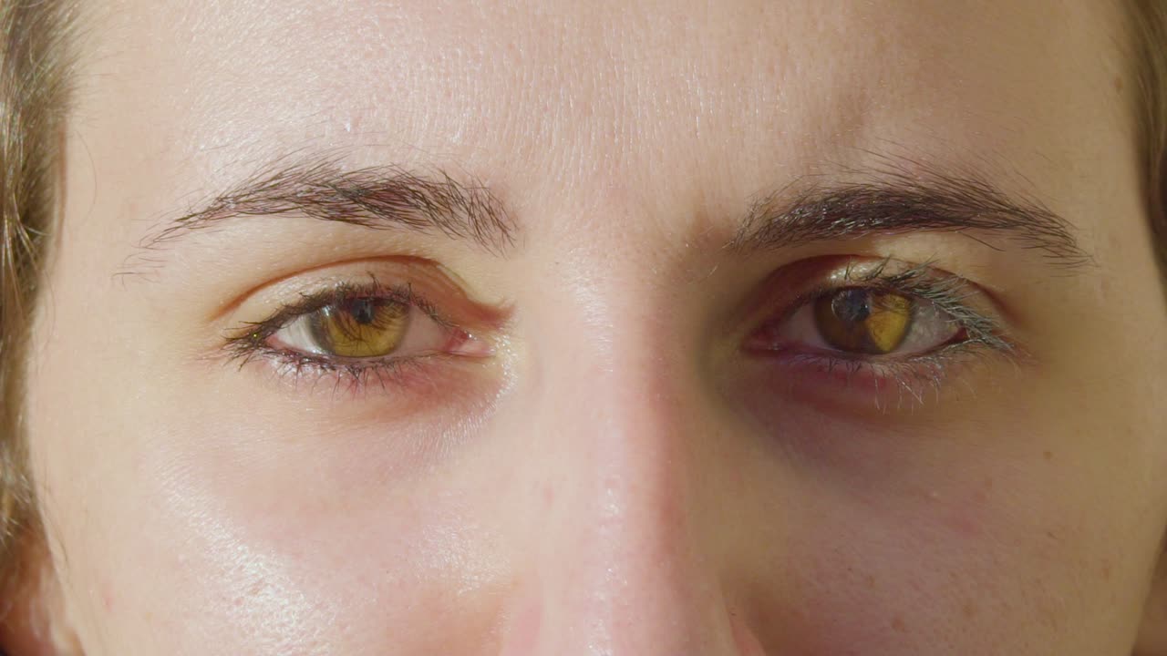 primer plano de los hermosos ojos marrones claros de la mujer caucásica mirando directamente a la cámara con relámpagos naturales