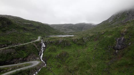 Volando-Hacia-La-Cascada-Y-El-Lago-Al-Lado-De-Una-Pequeña-Carretera-En-Un-Estrecho-Valle-En-Senja-En-Noruega