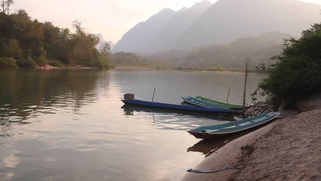 Canoas-Atracadas-En-La-Orilla-Del-Río-En-La-Ciudad-Montañosa-De-Nong-Khiaw-En-Laos,-Sudeste-De-Asia