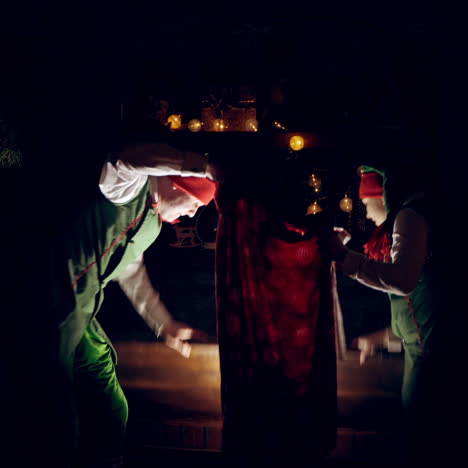 elves open magic box. two elves in the dark room at christmas. fairy characters taking red bag from magic coffer.