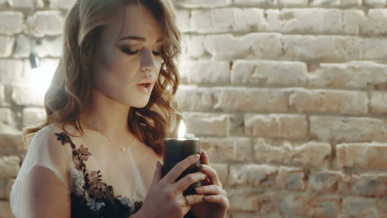 Witch woman holding candle. Close up of woman in a witch suit on ritual with candle in room