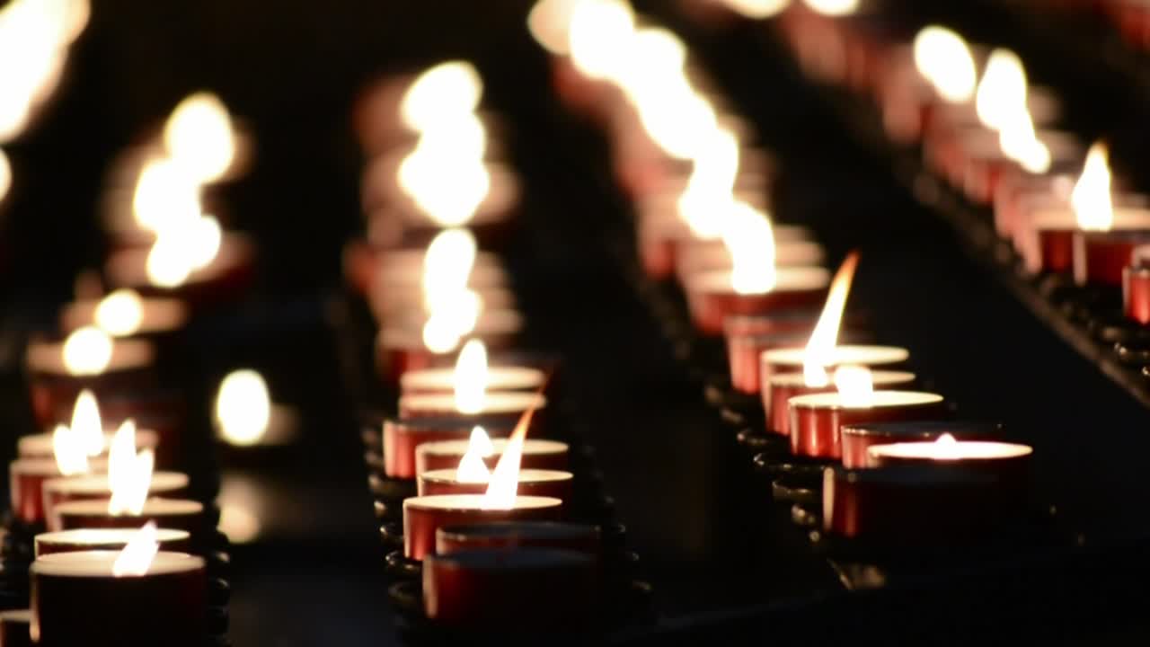 muchas velas rojas encendidas en una iglesia oscura