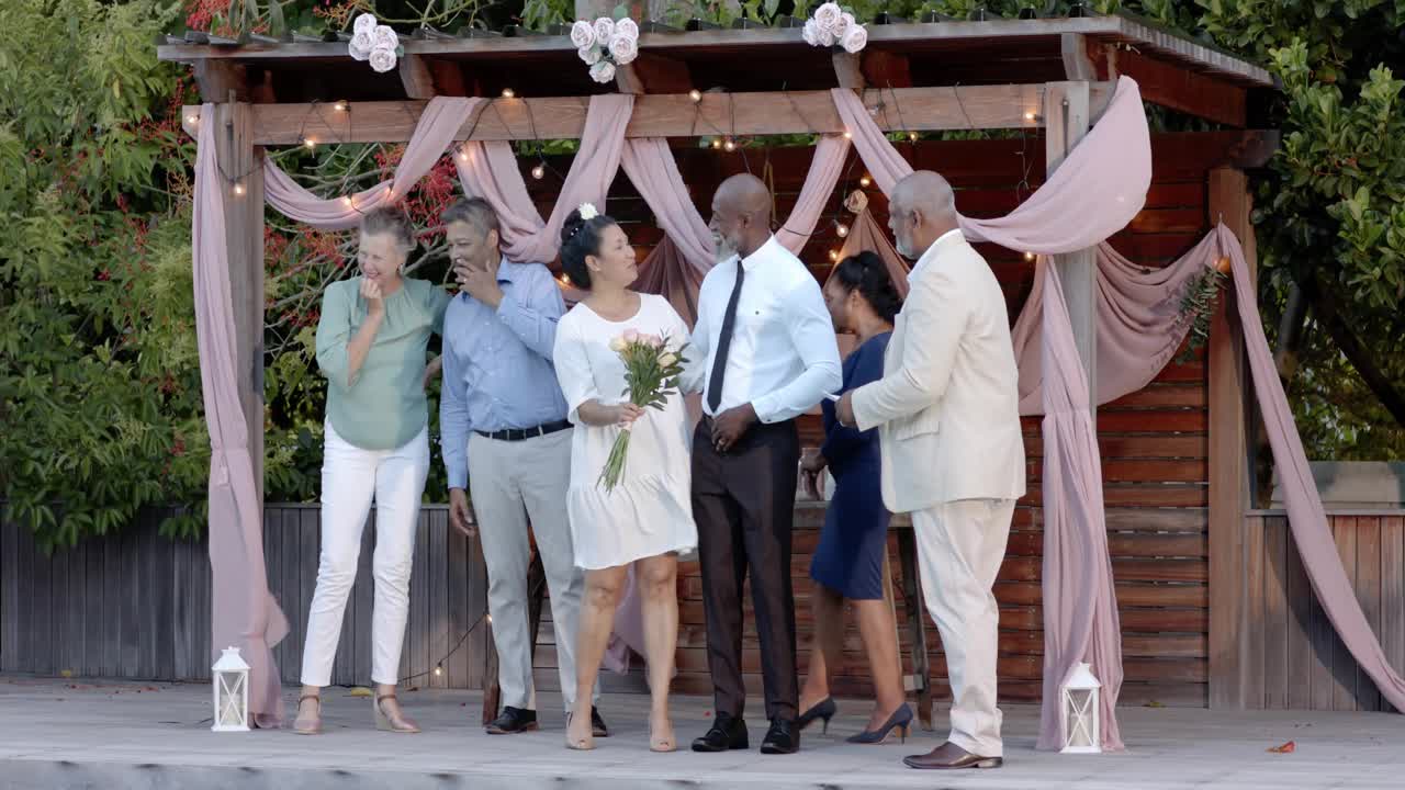 Celebrante che legge le promesse, coppia che si fa avanti sulla piattaforma del pergolato nuziale, cuori animati che fluttuano