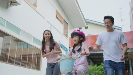 family teaching a child to ride a bike