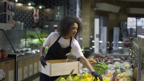 Trabajador-Multirracial-Con-Delantal-Negro-Almacenando-Pimientos-Amarillos-En-El-Supermercado