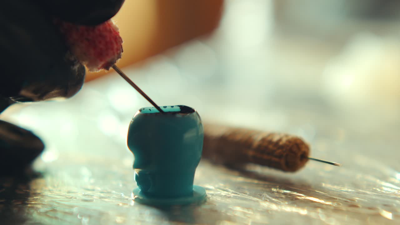 Extreme Close-Up of Tattoo Artist Dipping Needle in Inks